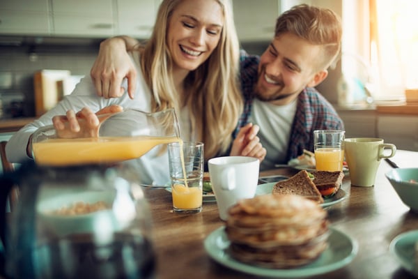 Young couple having breakfast together laughing