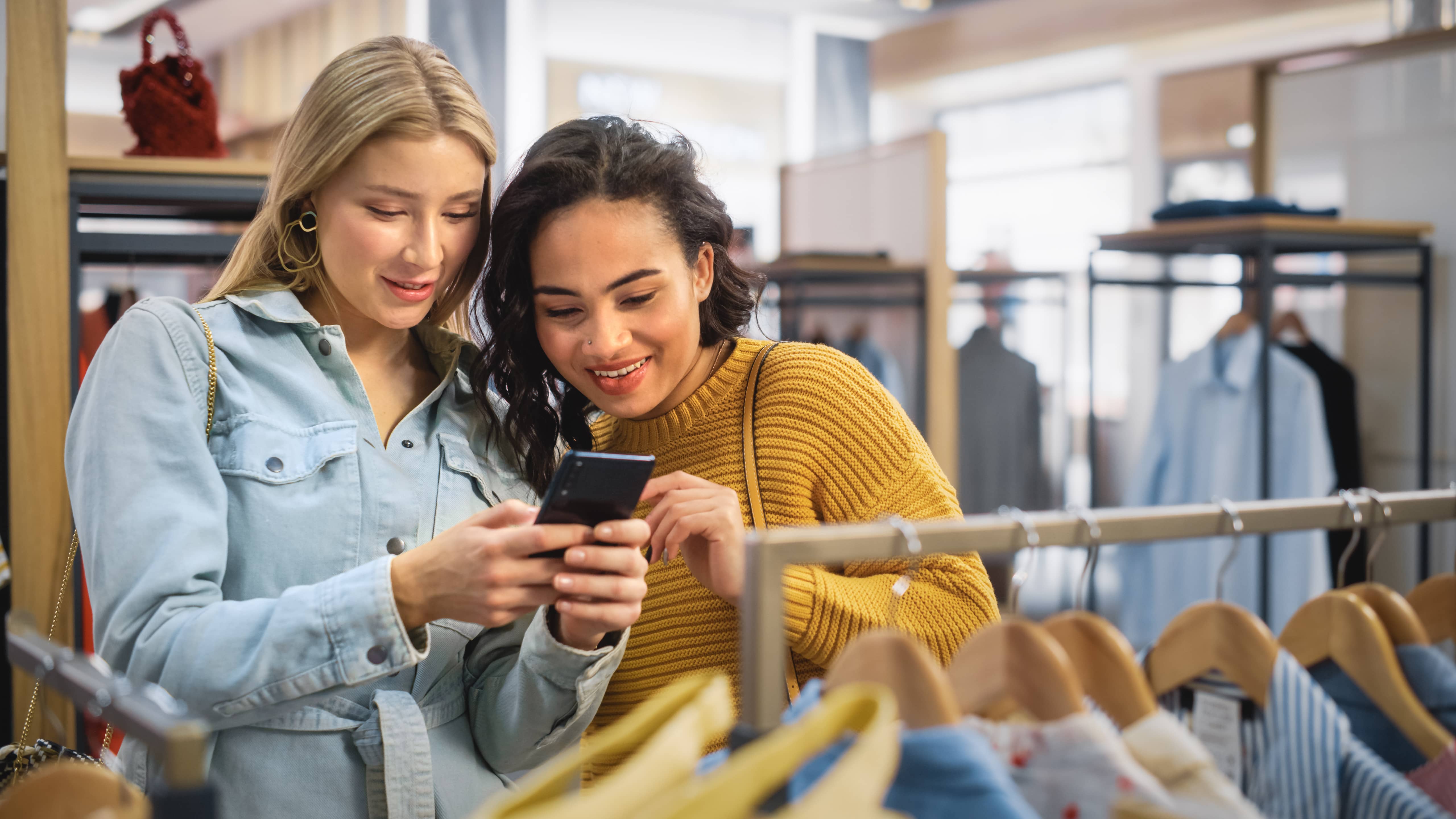 Two teenage girls on their phones and shopping.