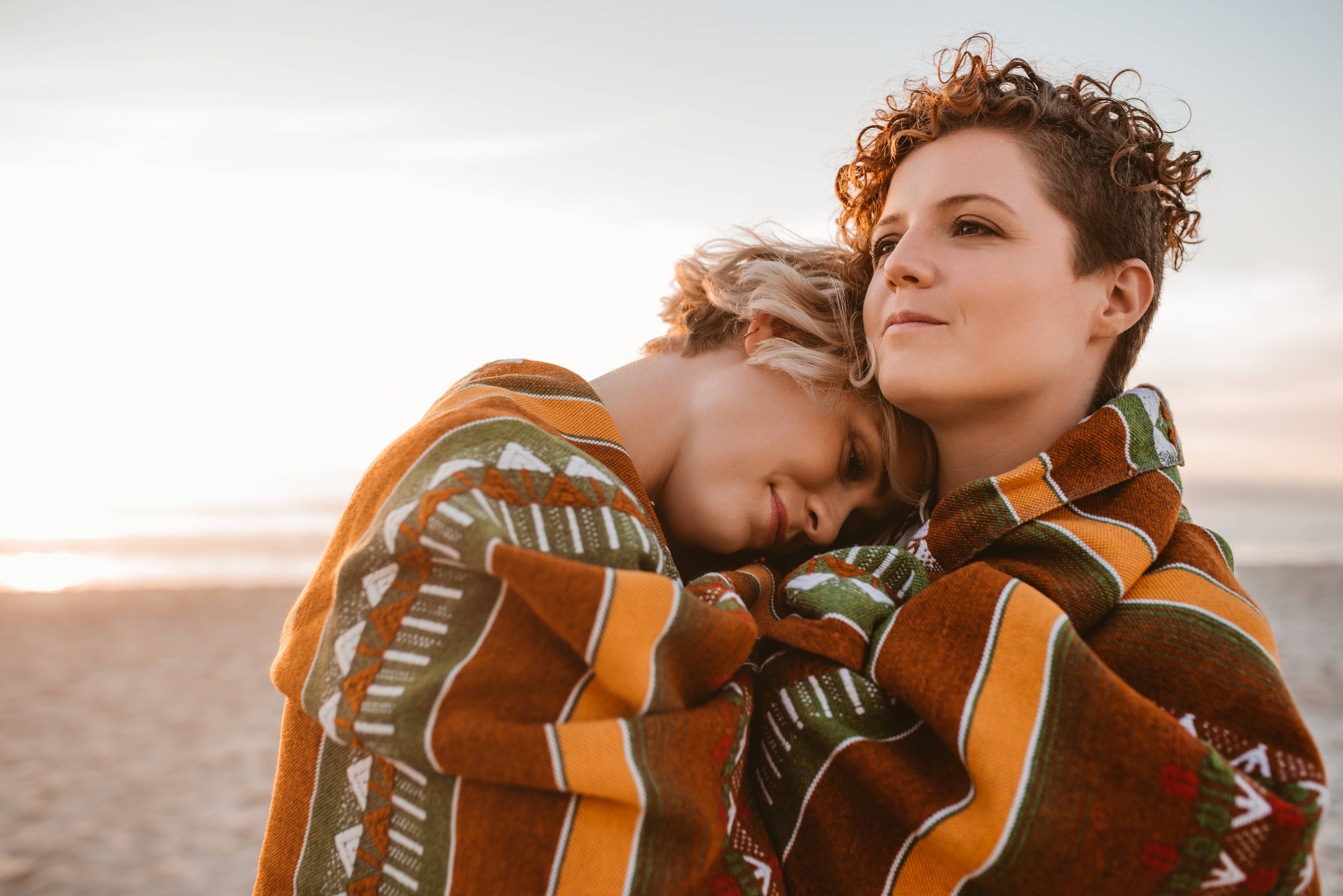 Two women wrapped in colorful wool blanket