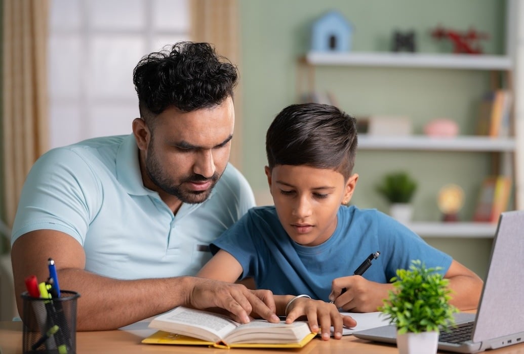 A father helping his son with reading and a language assignment.