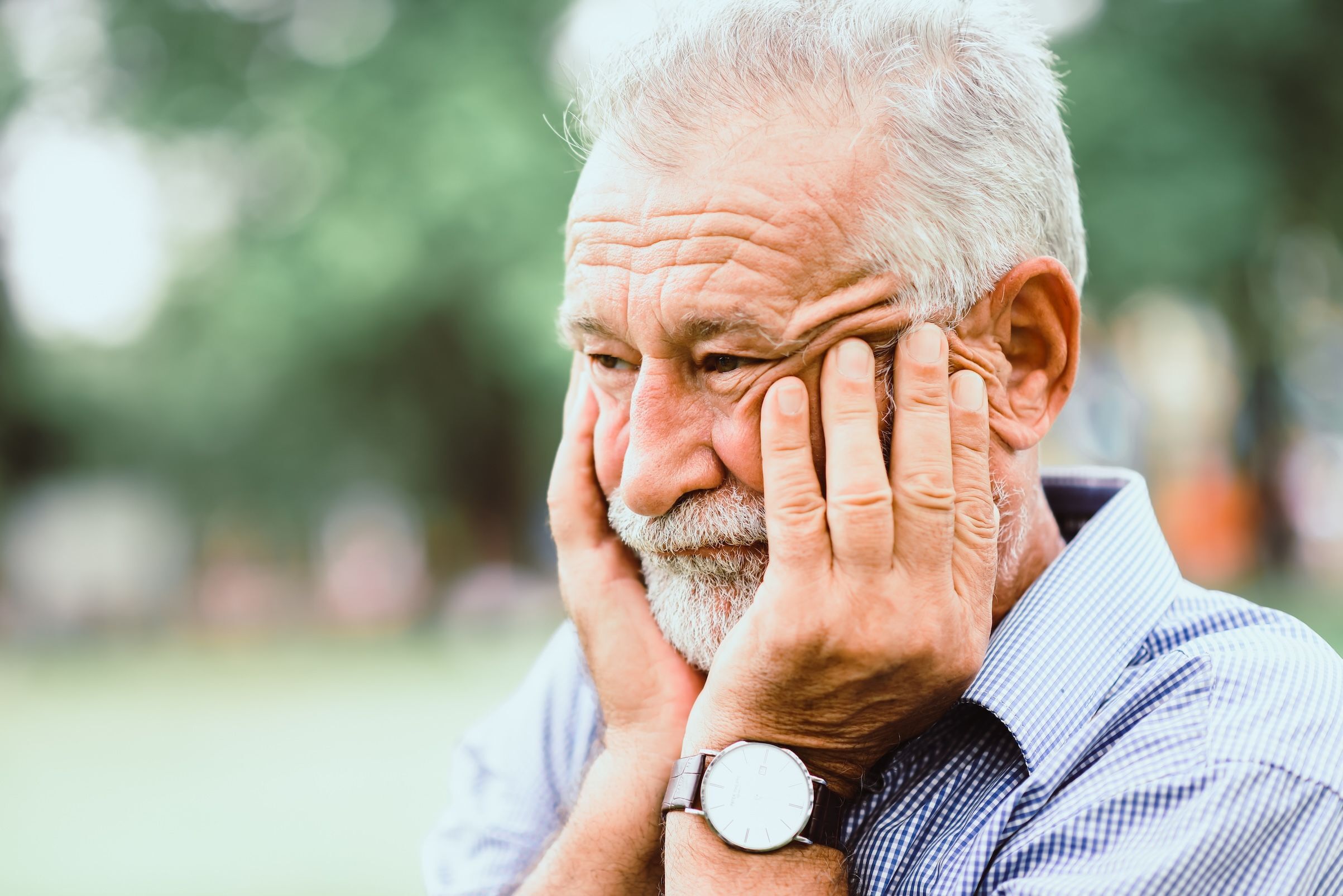 A father of an adult son leaning on his hands with a serious and sad expression.