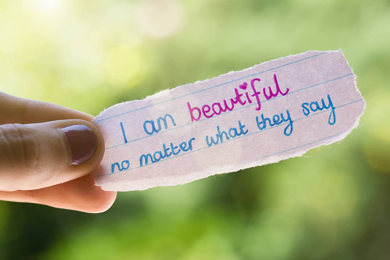 A handwritten self-affirming note held by a woman's hand who is rewiring limiting beliefs