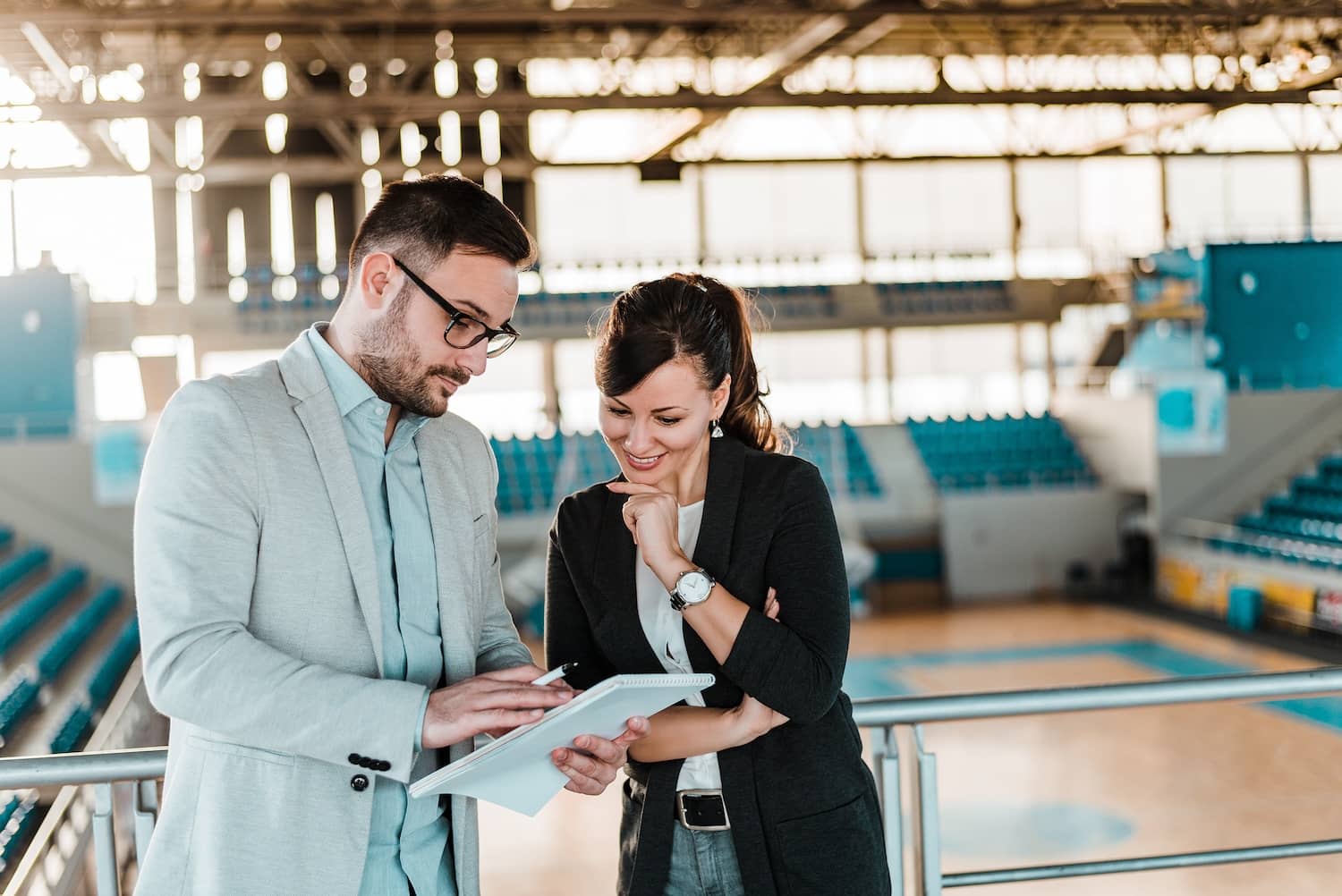 A sports manager giving tips and feedback to another manager at a sports hall.