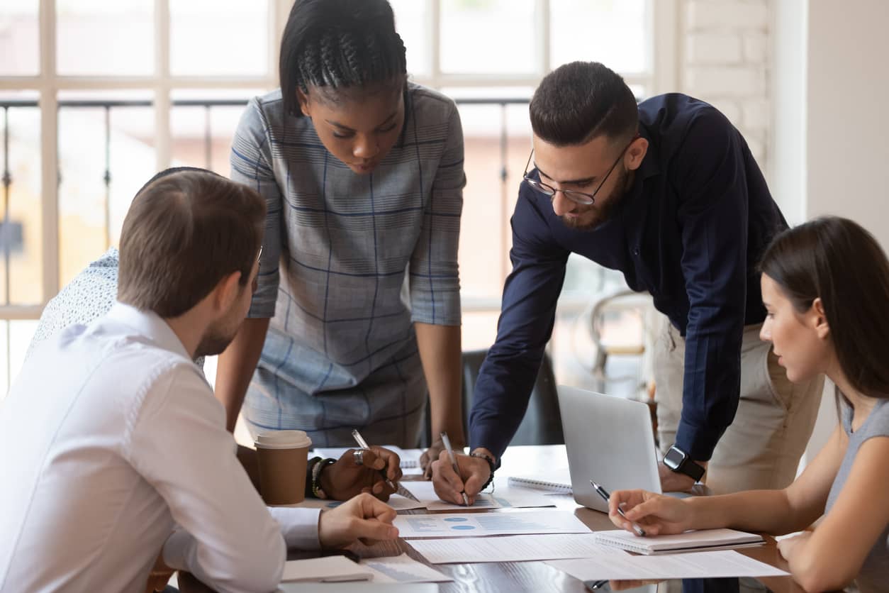A team of focused, multi-racial employees at a corporate business brainstorming together.