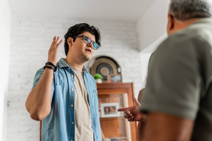 A young man and his father arguing at home.