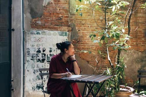 A smiling Asian woman reflecting and having a moment of introspection.