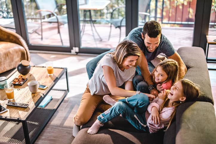 An aerial view of a family being playful on the couch.