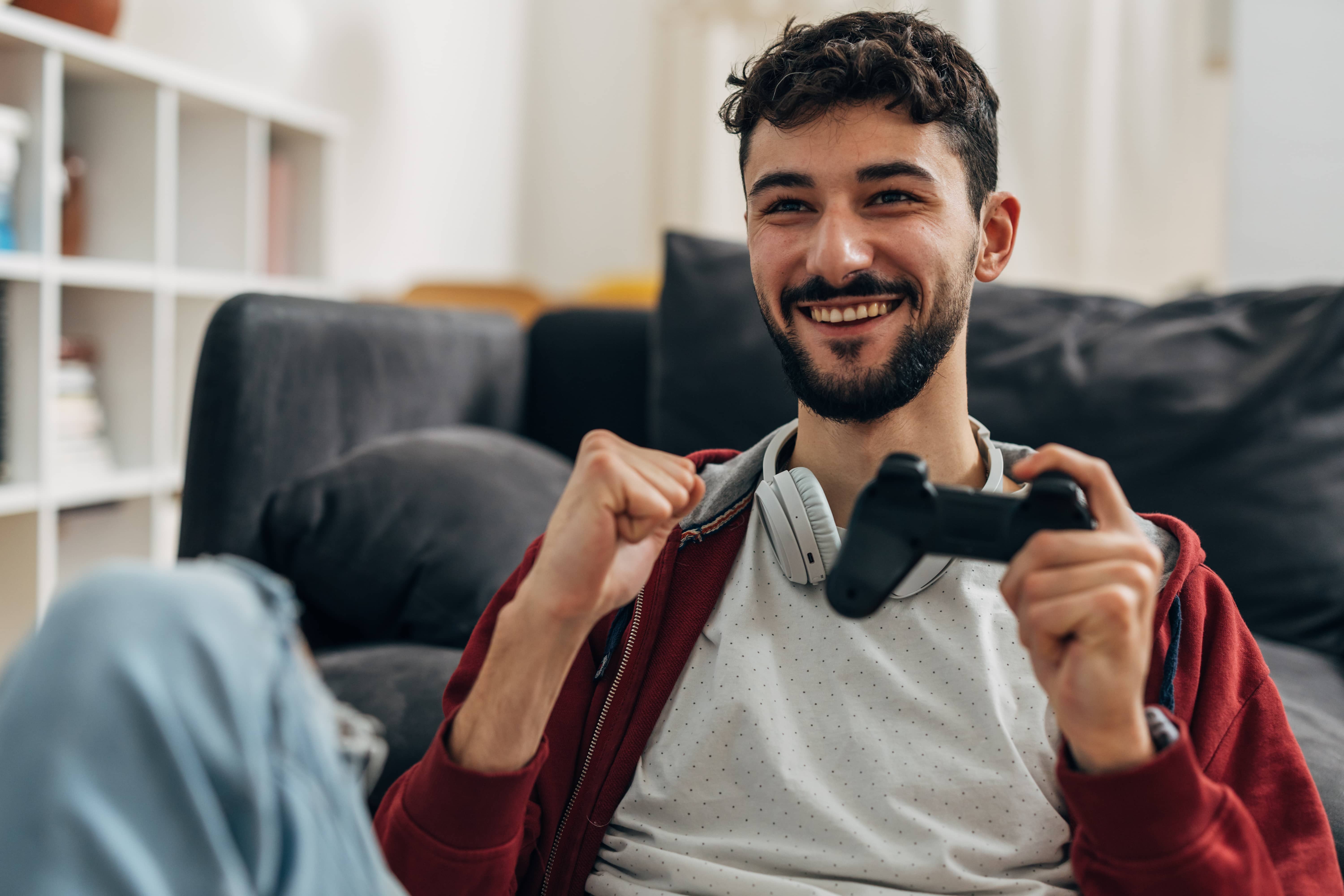 Young adult man playing video games while living with his parents.