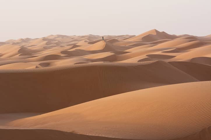 Single man walking in the desert dunes of the Wahiba Sand Desert