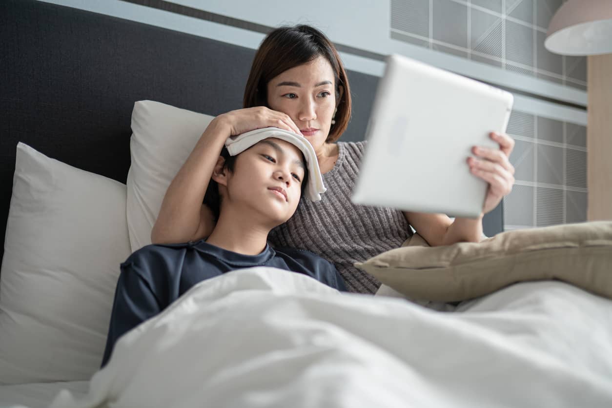 Asian mother comforting her son who has a fever