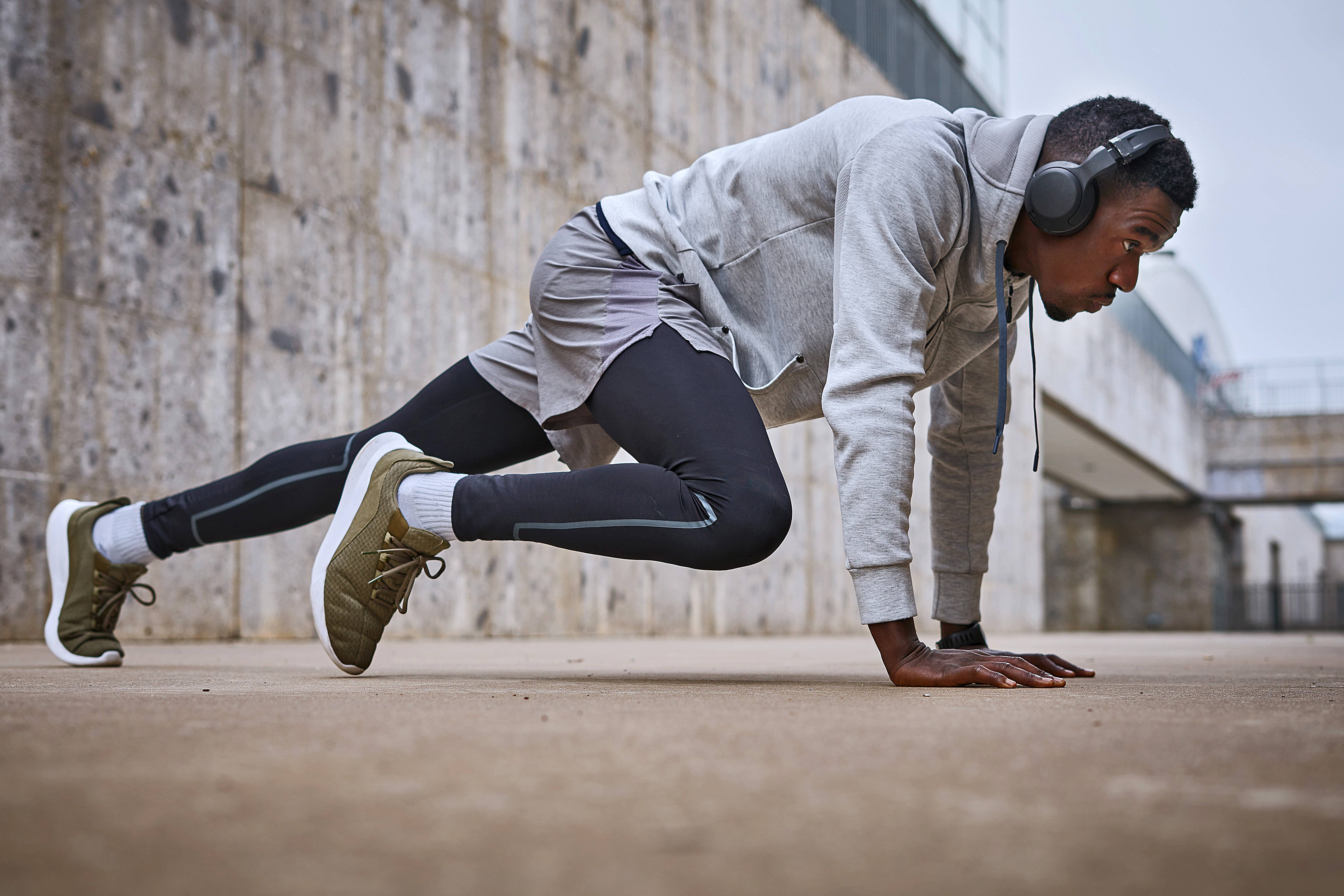 Athletic man exercising near the grey wall in the morning.