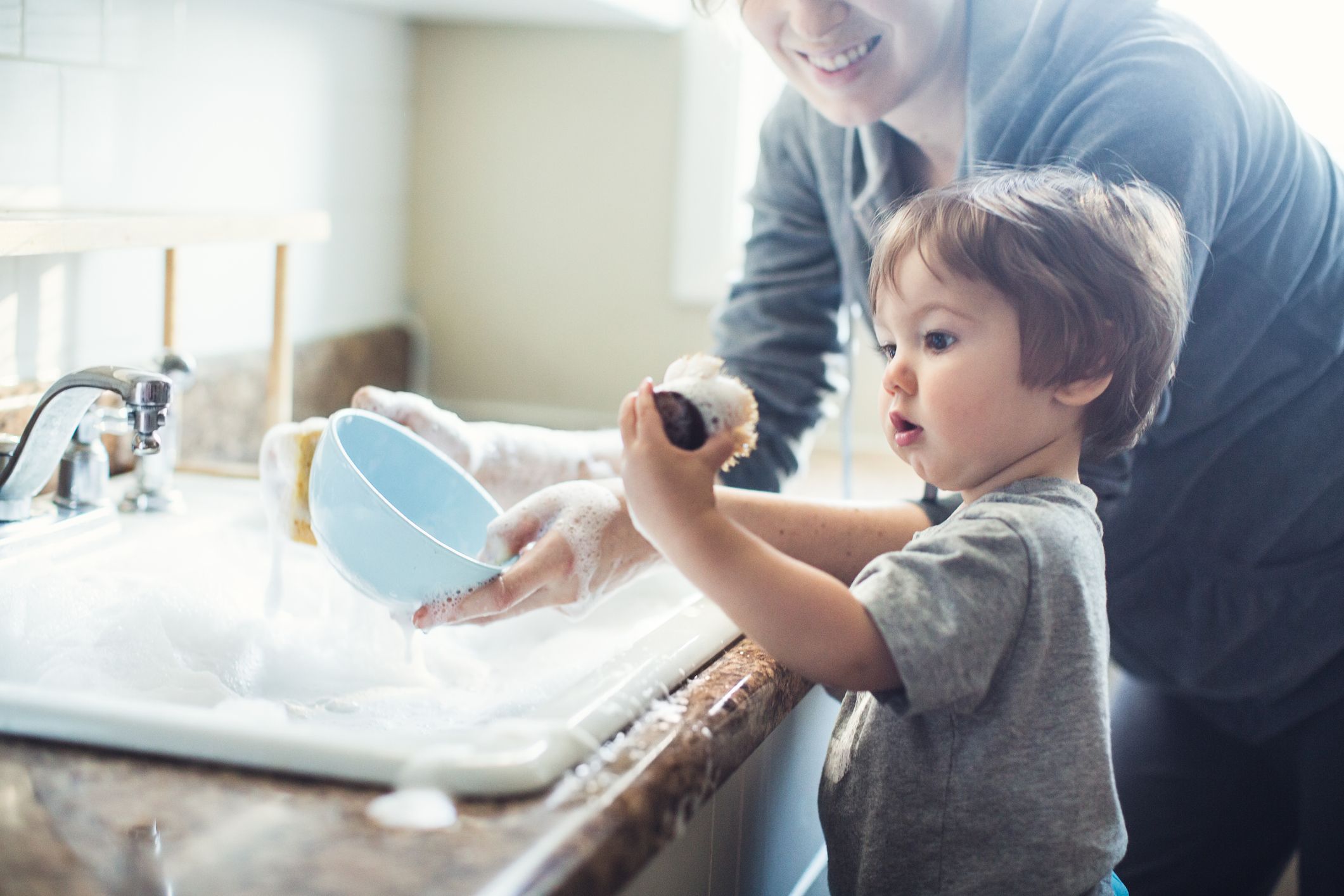 A toddler helping with dishes; one way to apply Montessori in the home.