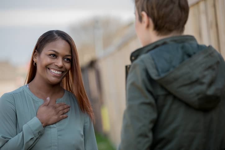 A beautiful African American woman smiles while her partner expresses appreciation.