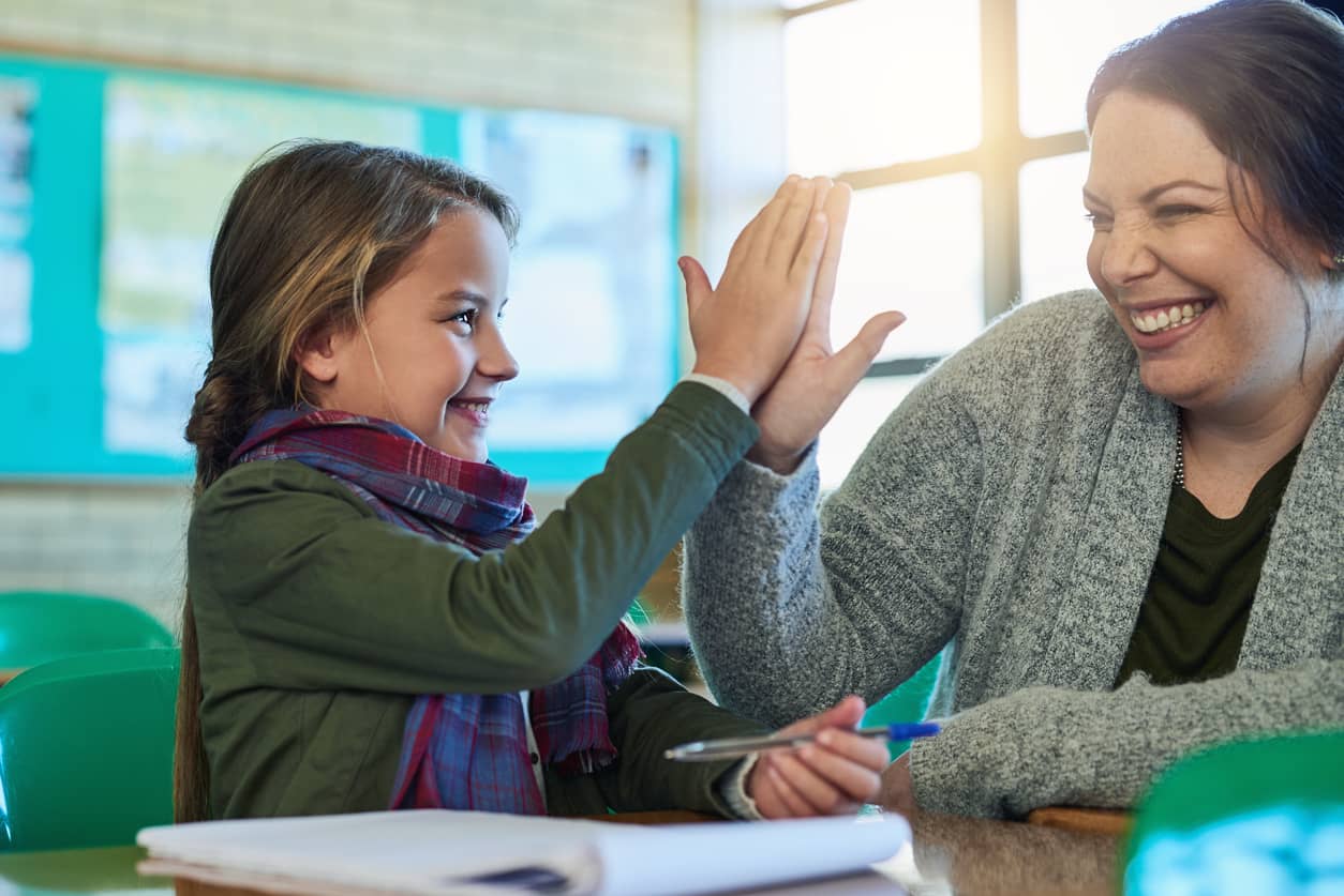 A teacher celebrating an accomplishment with her elementary student with a high five.