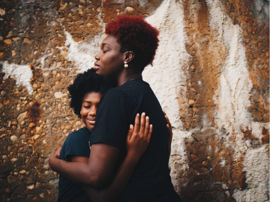 A black woman hugging her daughter to comfort her.