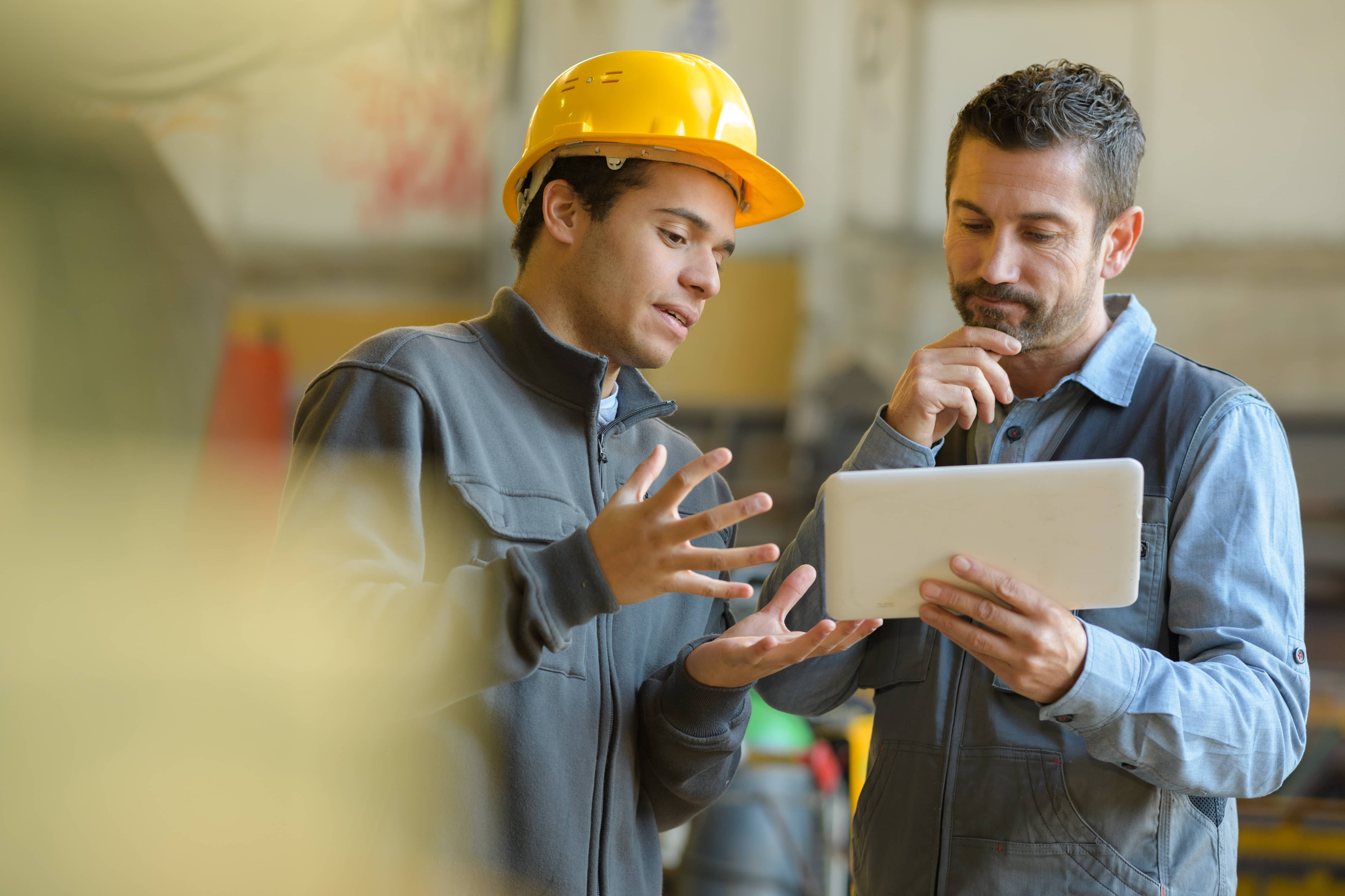 Construction workers consulting a building plan on an I-pad.