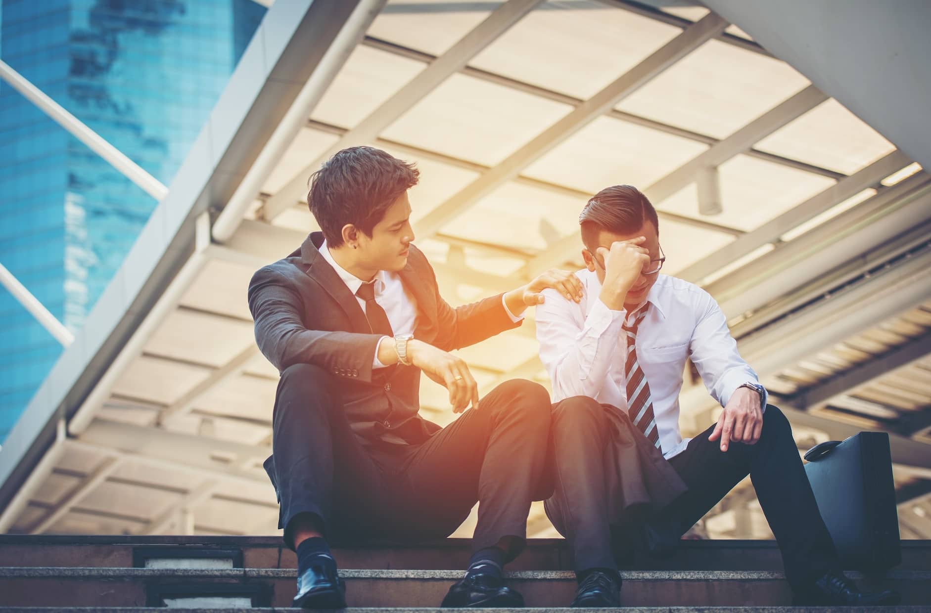 Empathy in the workplace - a business man giving empathy and comfort to a coworker.