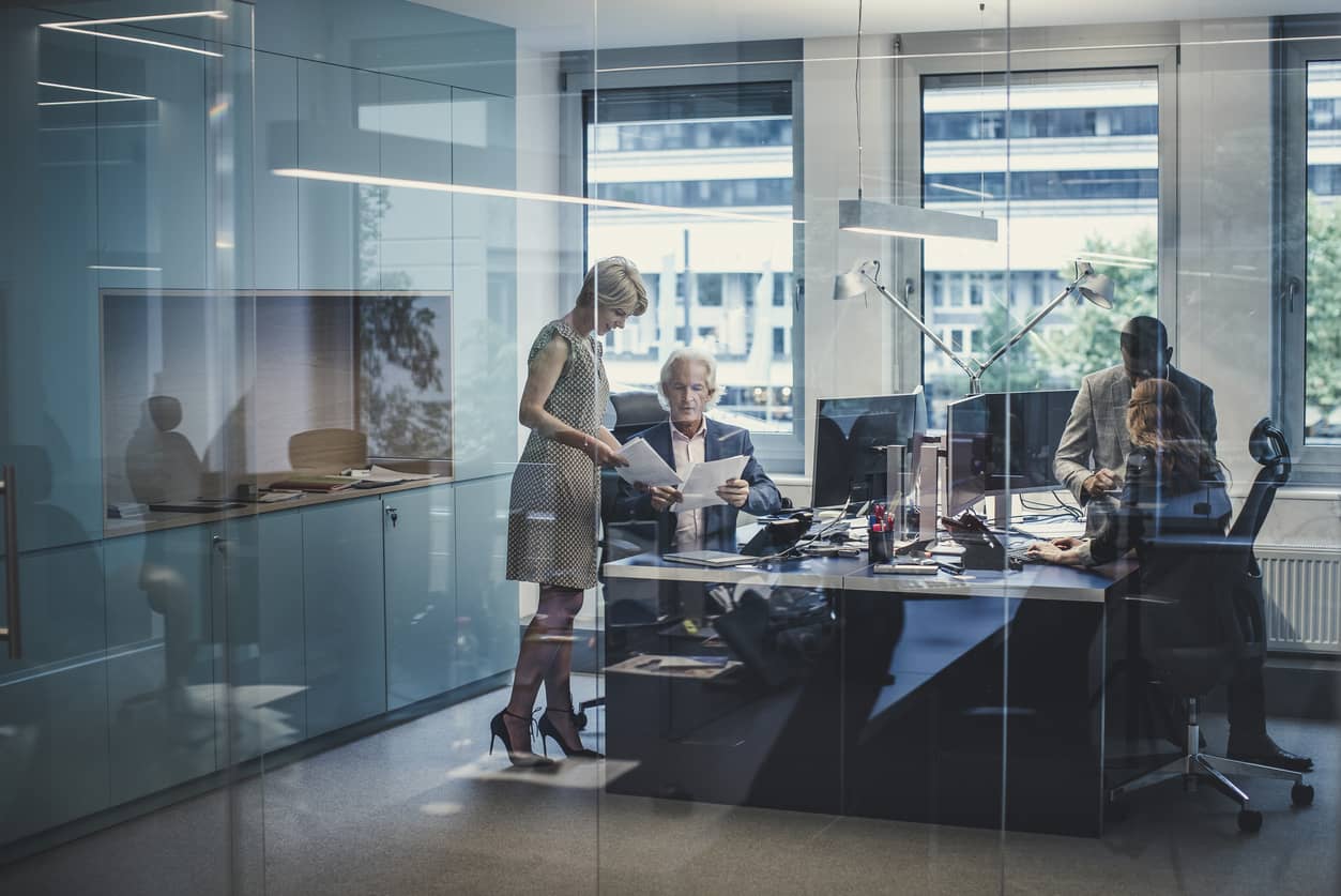 An empathetic leader working with his team in a glassed-in office.