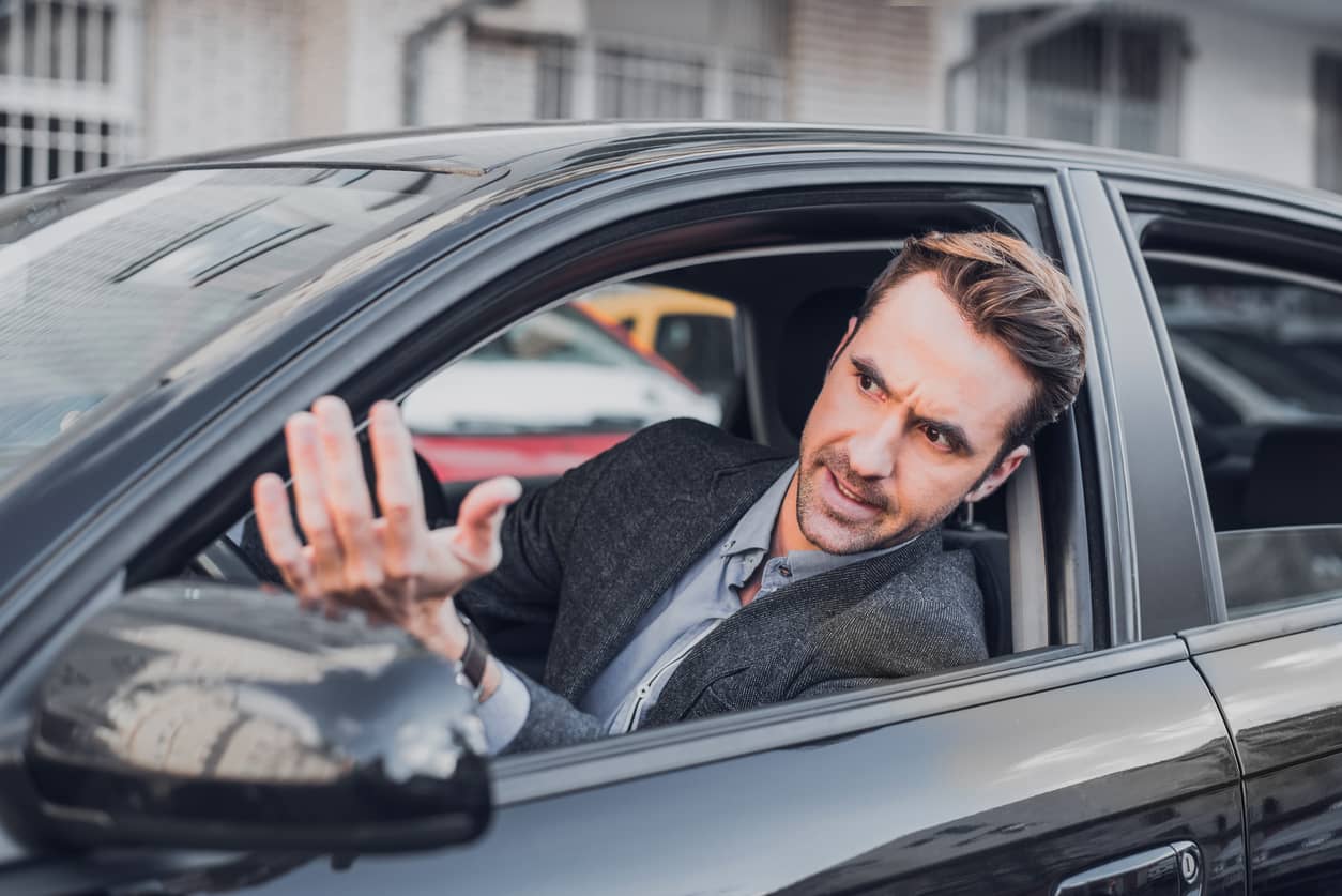 An angry businessman driving and upset with other drivers. How to control anger/?