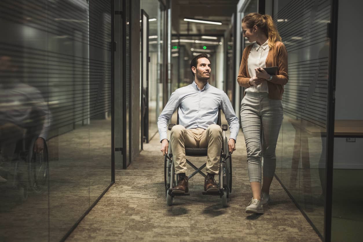 A businessman in a wheelchair talking a colleague at an inclusive workplace