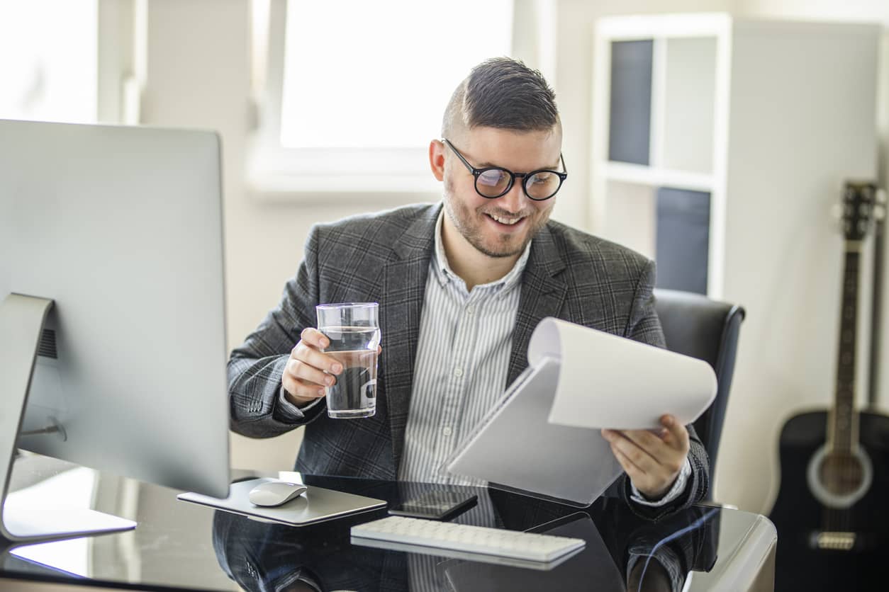 A businessman drinking a glass of water in his office.