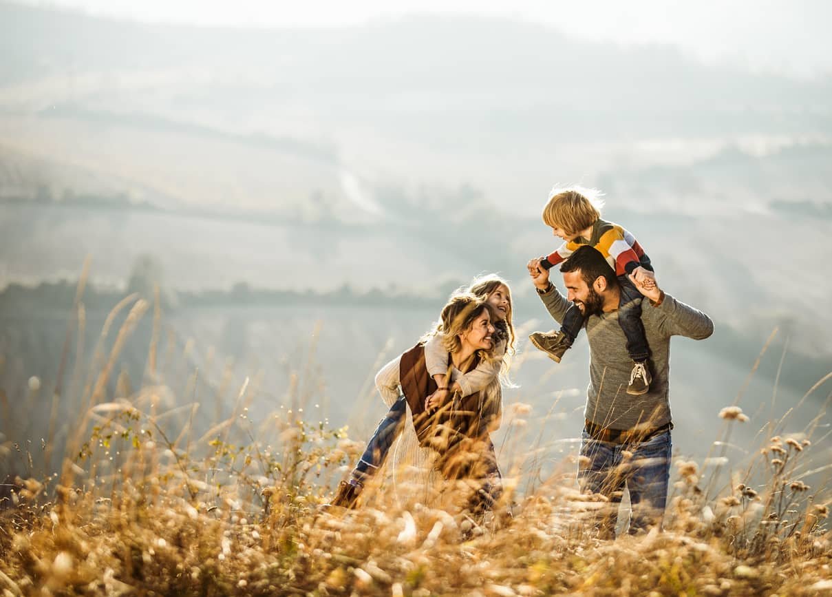 A young, happy family walking together in a field.