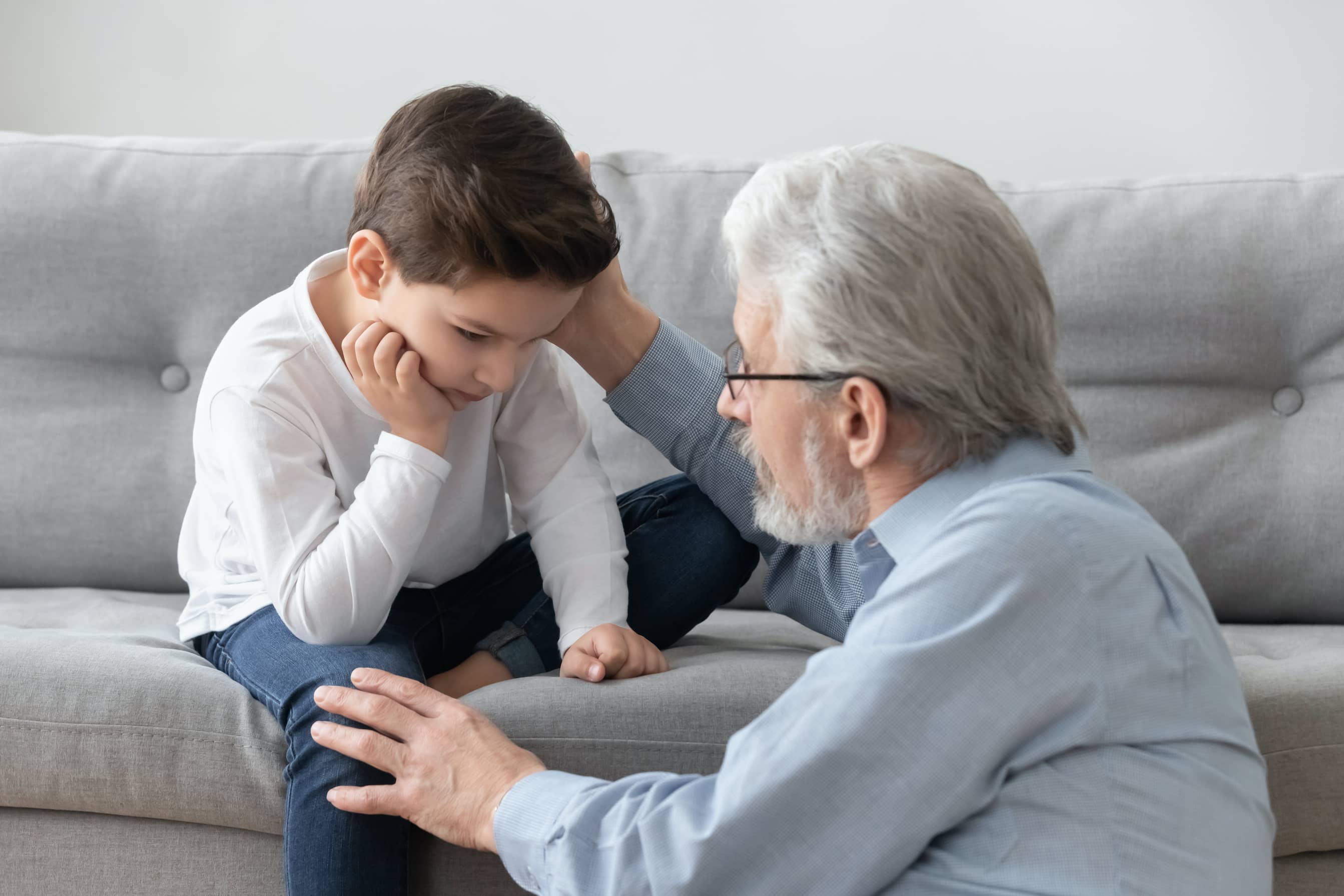 Caring senior grandpa comforting and giving emotional support to his sad grandson .