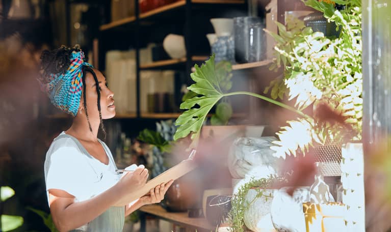 Checking inventory - a black woman works on a floral growth inspection in her small business