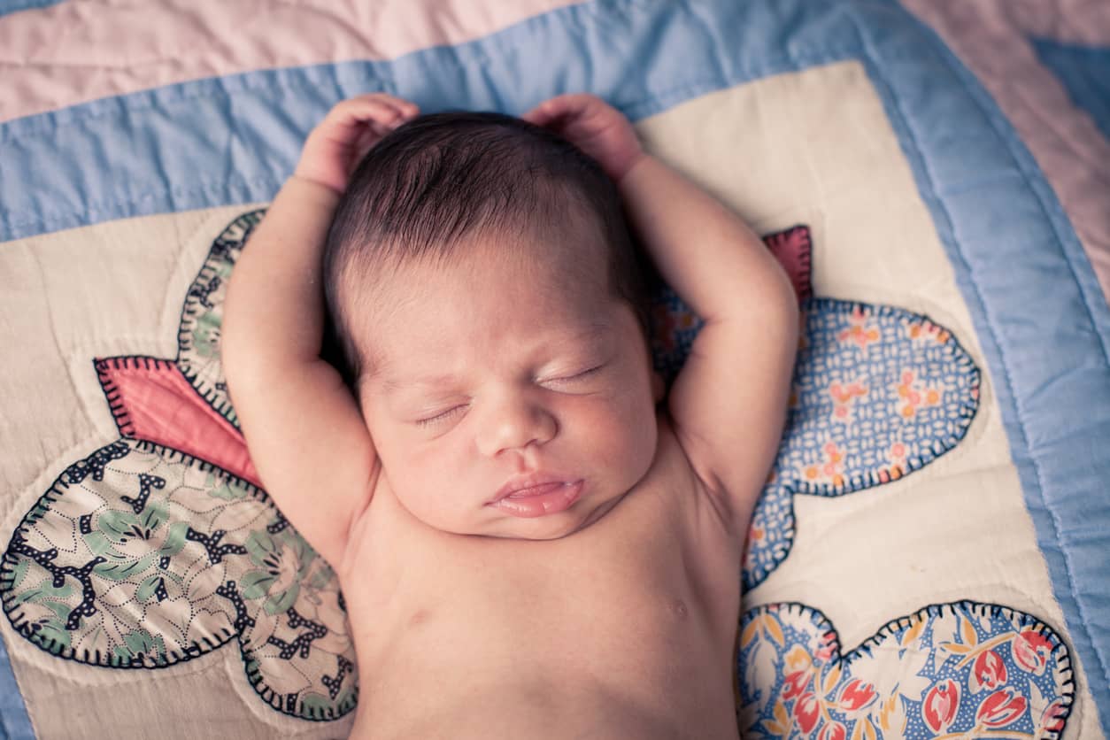 Newborn baby sleeping peacefully on a Baby Memory Quilt