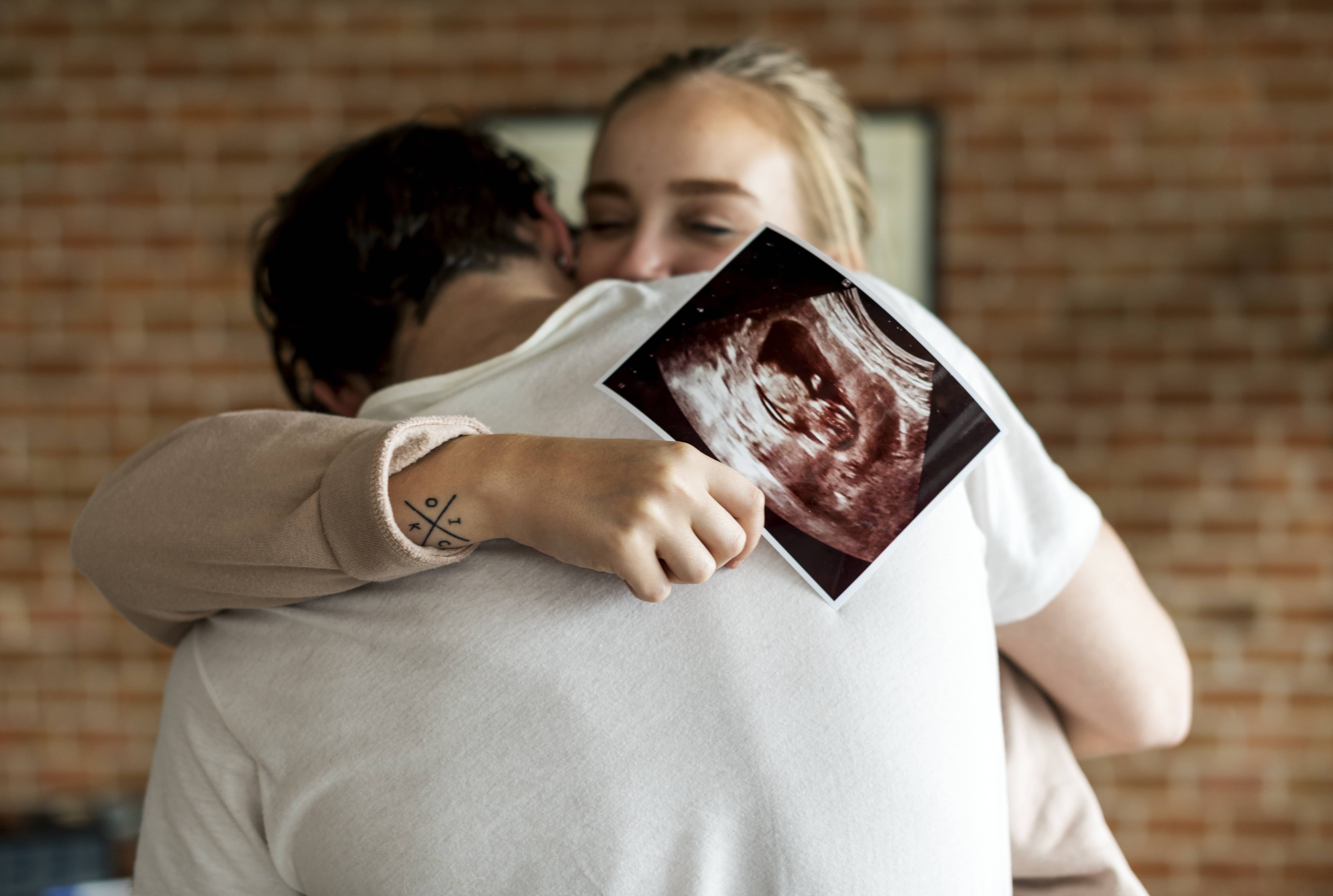 A couple hugging with an ultrasound of their baby