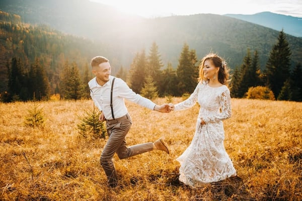 Married couple running through a golden field