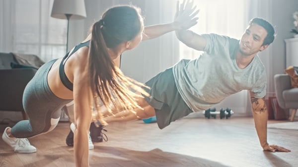 A married couple high-fiving while doing push-ups