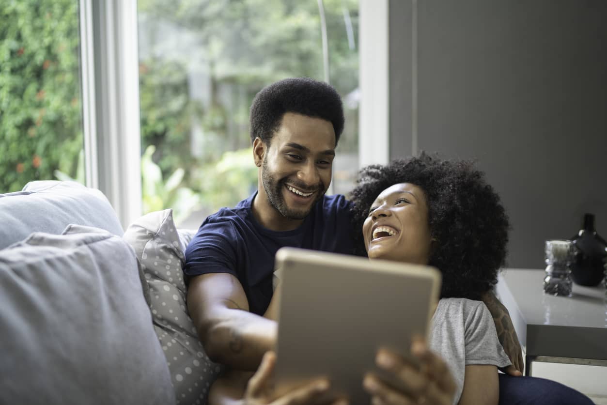 Couple laughing while using digital tablet.