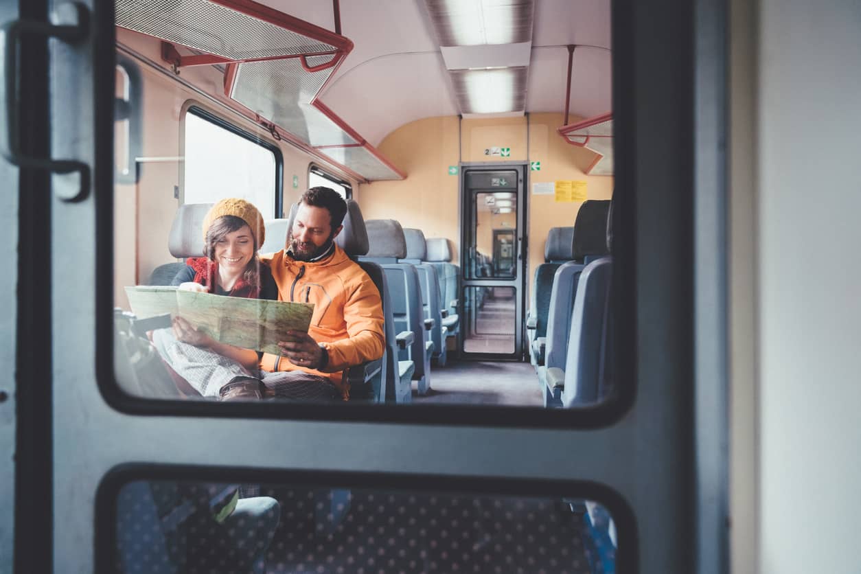 A young couple reading a map while riding on a train.