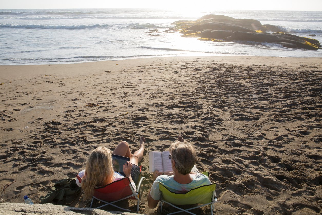 A couple reading on the beach at sunset