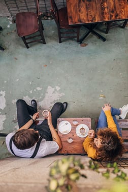 An aerial view of a couple sitting in a cafe talking.