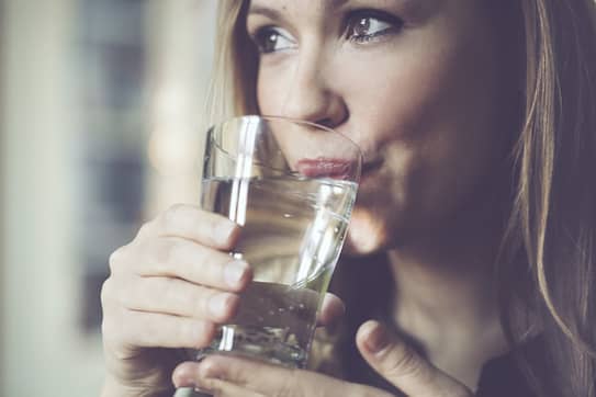 A young woman drinking water as a healthy habit.