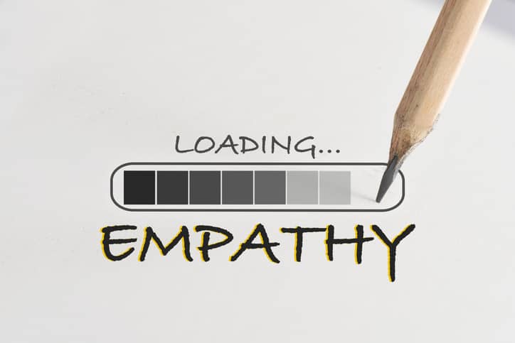 Empathy loading written on white paper with processing symbol and pencil