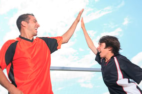 Father and son expressing elevated emotion as they high five each other