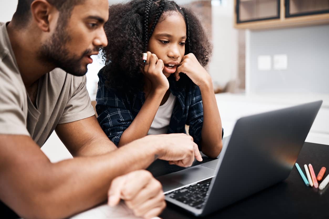 Father helping his teenage daughter on a laptop with a school assignment