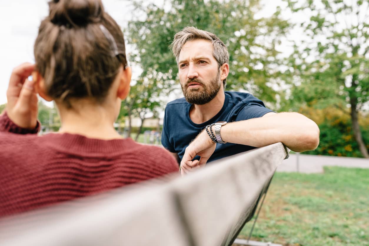 A father empathizing with his teenage daughter on a park bench.