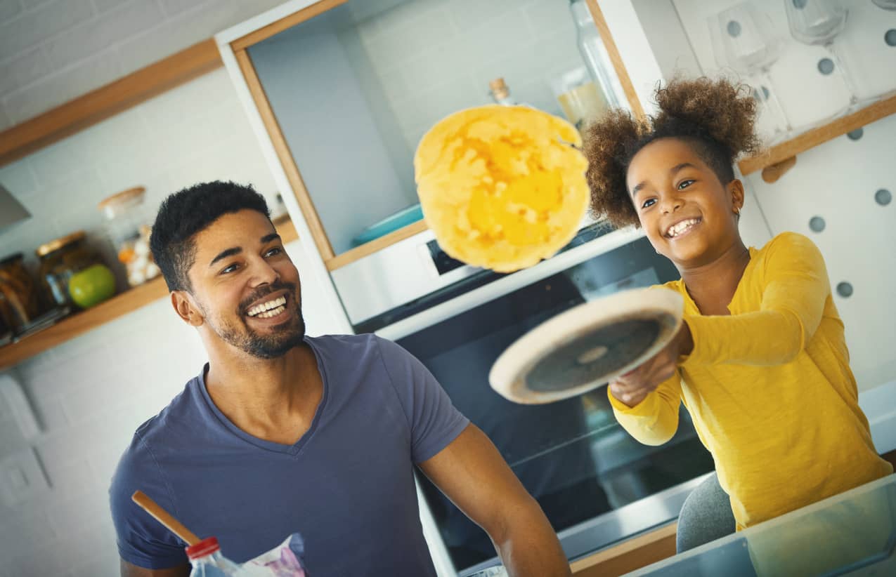 Father and daughter having fun and cooking eggs in the kitchen.