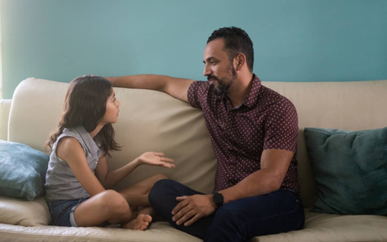 Father and daughter sitting on sofa and arguing.