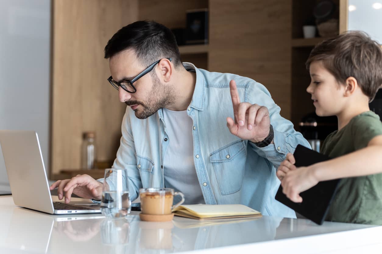 Father working from home while his son is trying to get his attention.