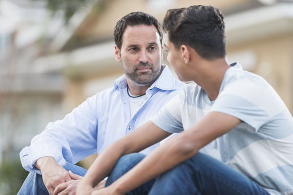 Father listening intently and empathizing with his teenage son 