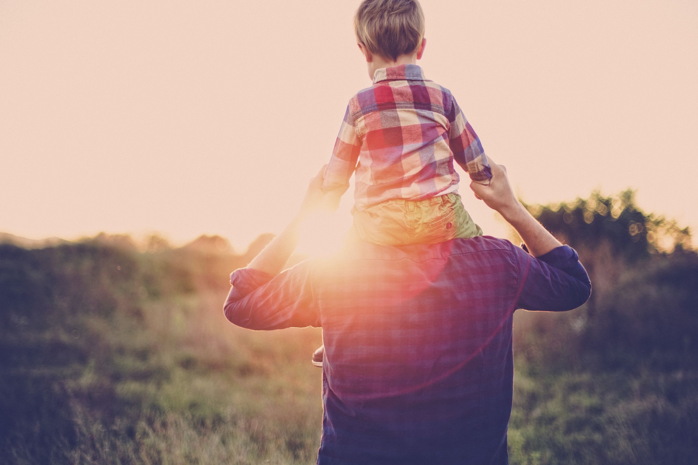 Father with son on his back with the sun shining on Father's Day.