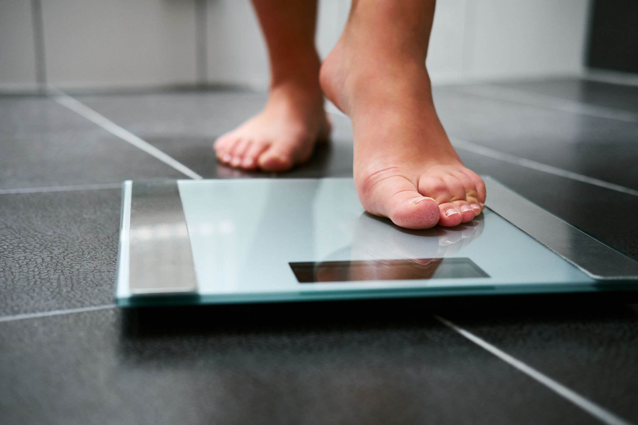 Bare-foot woman weighing herself and tired of being fat