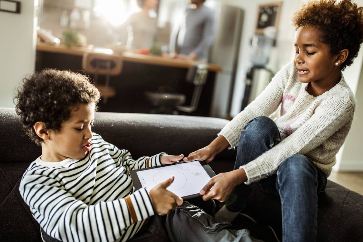 Two siblings fighting angrily over a touchpad