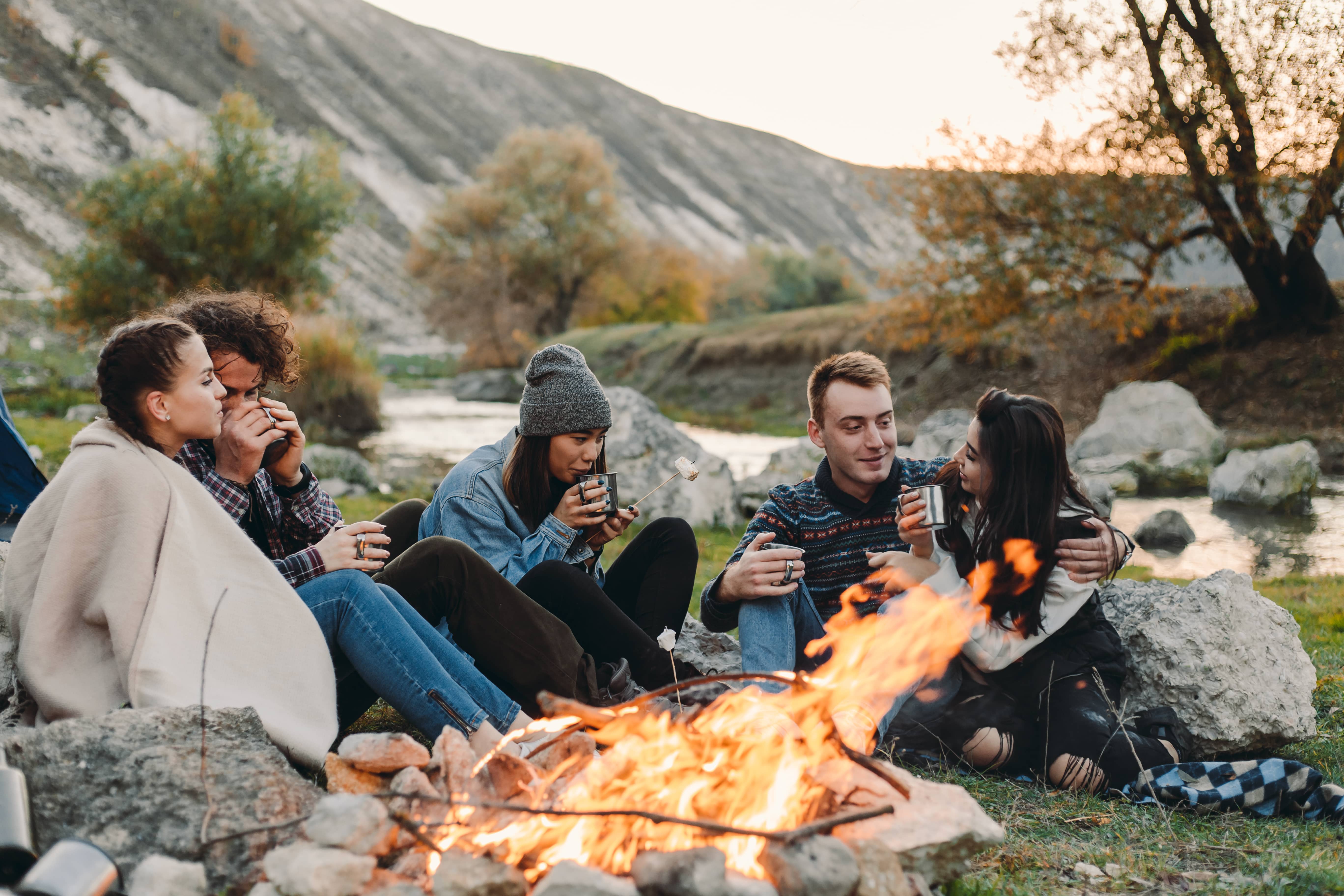 Friends around campfire by the river.