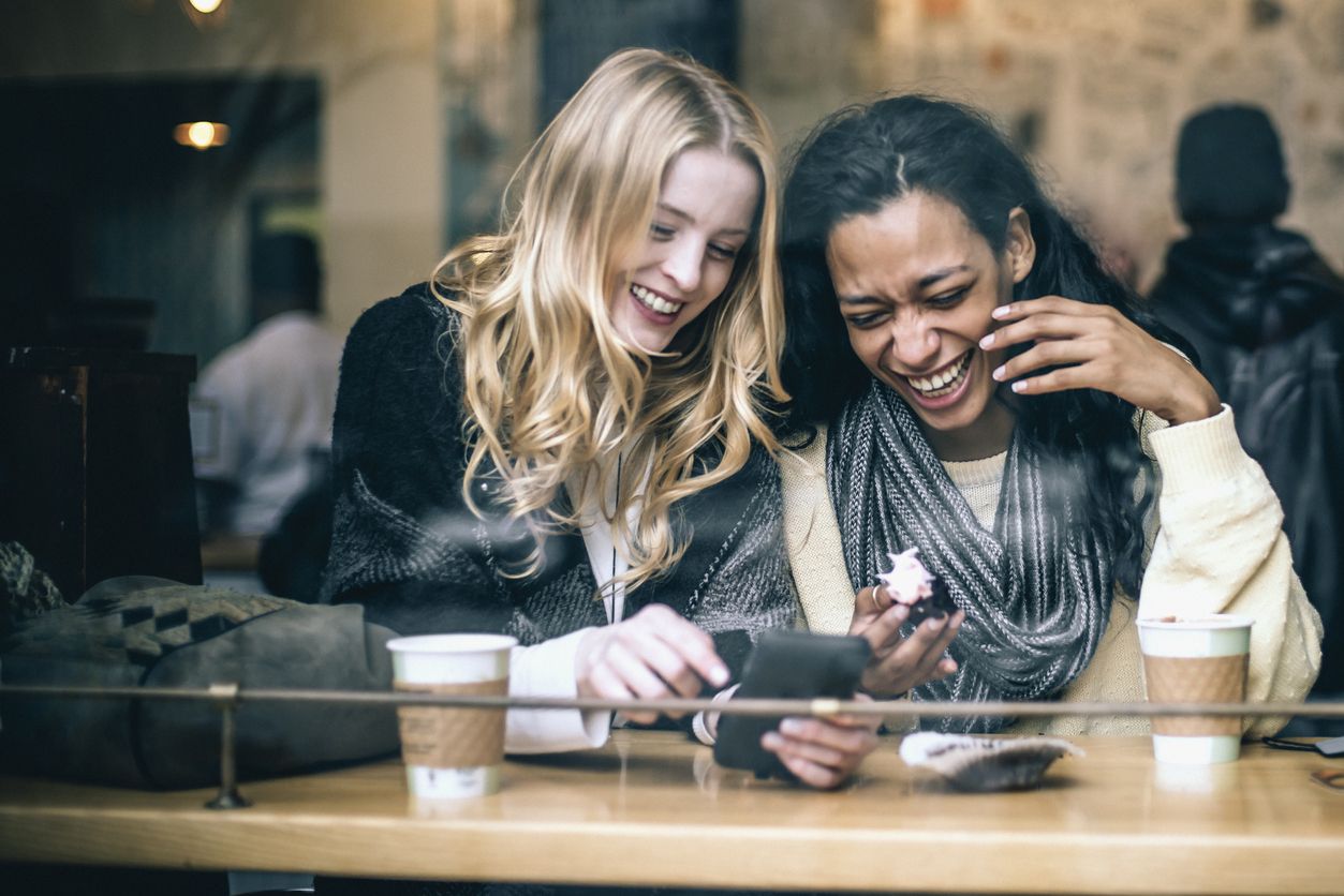 Two women laughing at a coffee shop